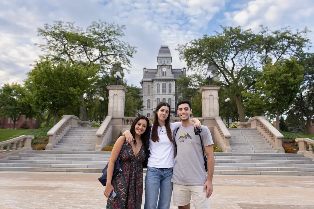 International students standing outside of the Hall of Languages smiling.